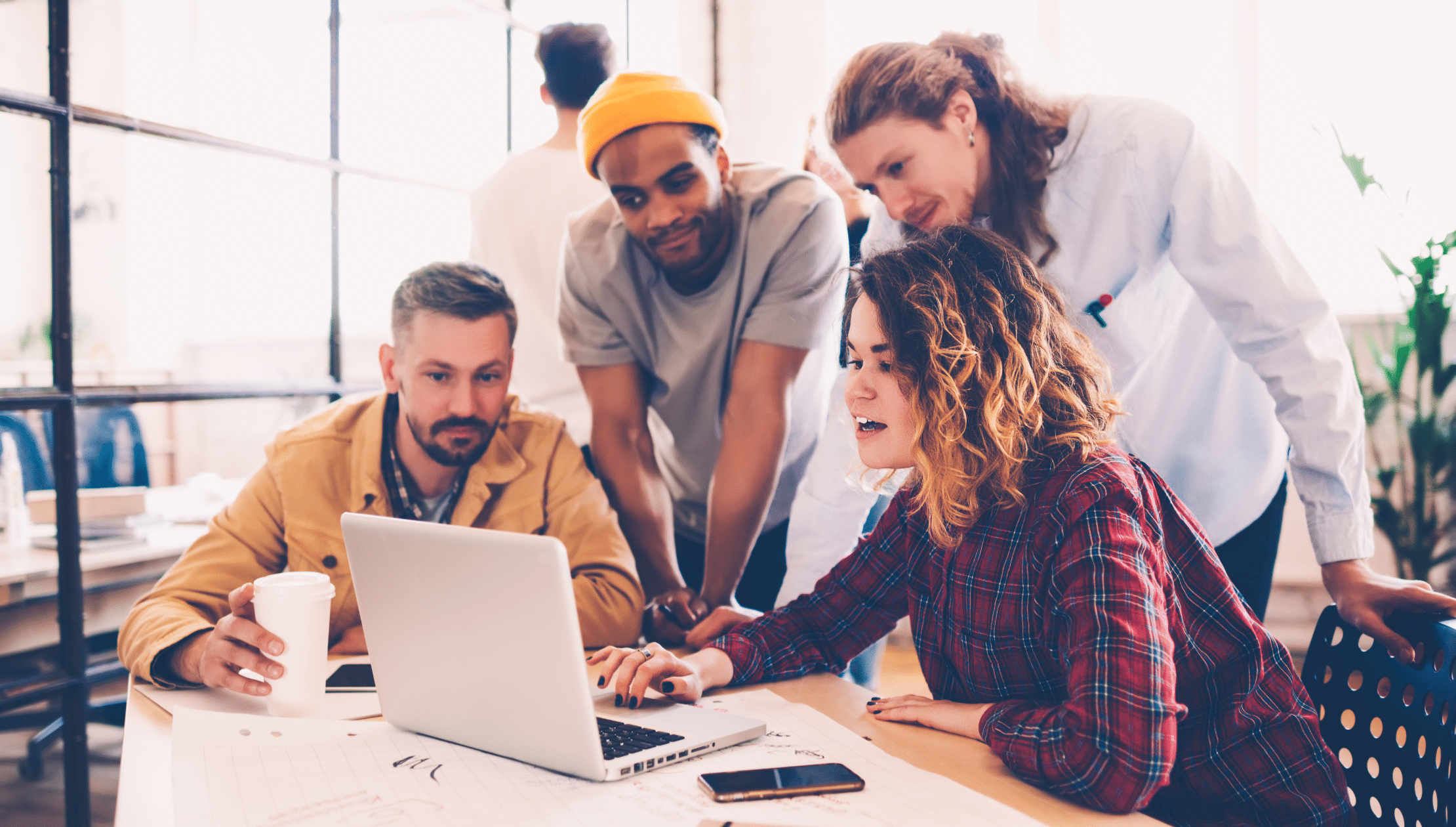 Office workers collaborating around a latptop