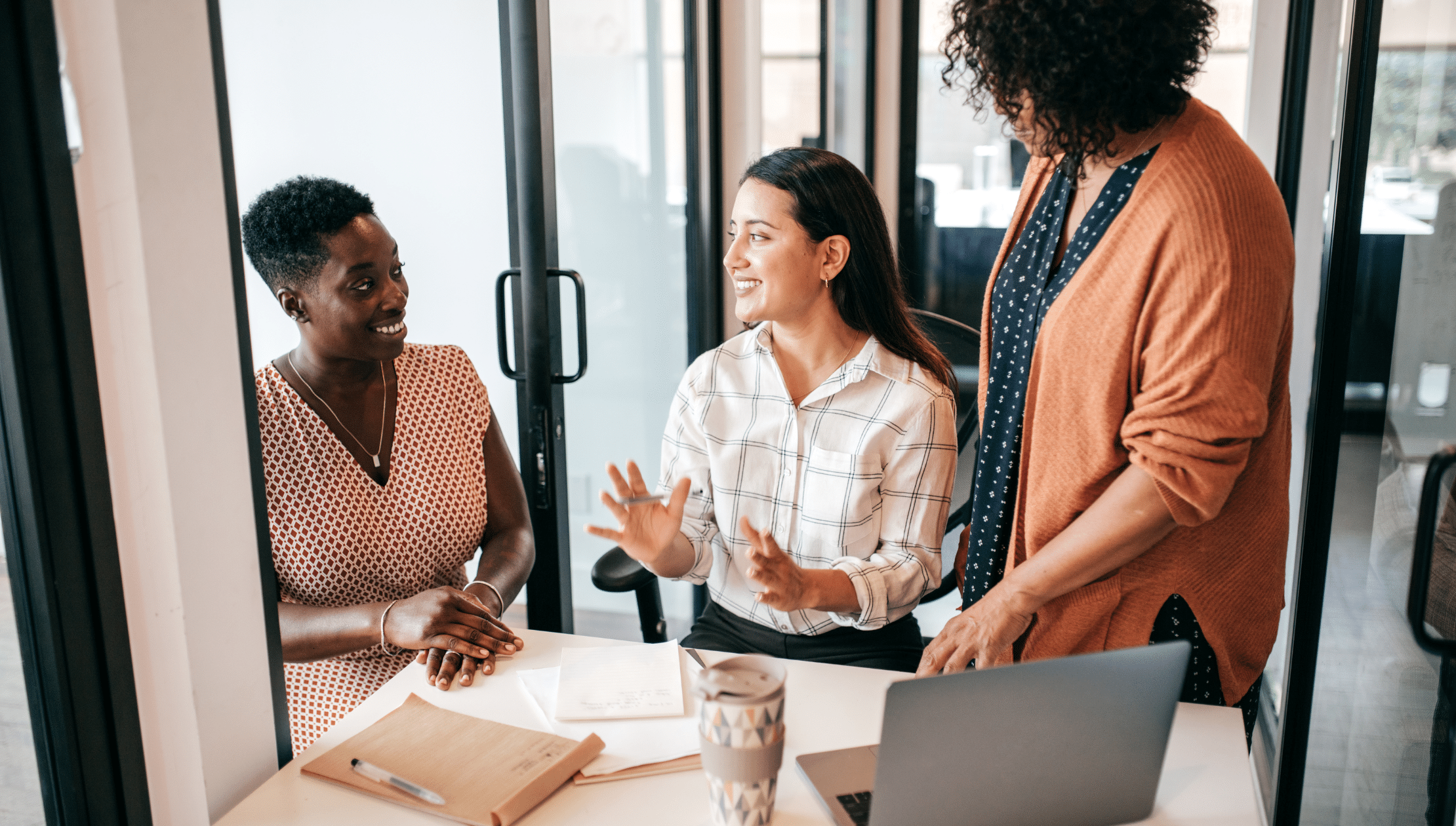 Three women of different races collaborating in an office setting.